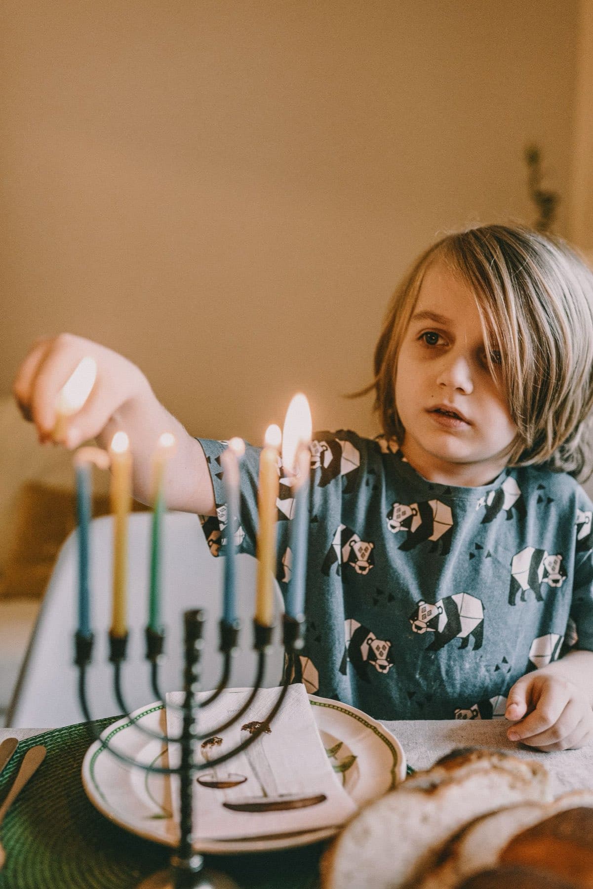 Boy lighting the candles on a Chanukah menorah