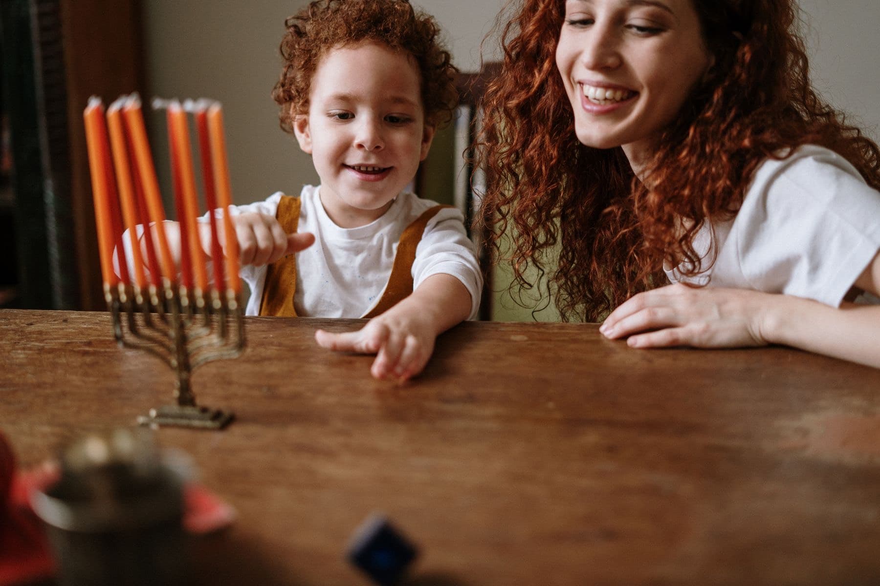 אמא ובנה הקטן מחייכים ליד חנוכייה