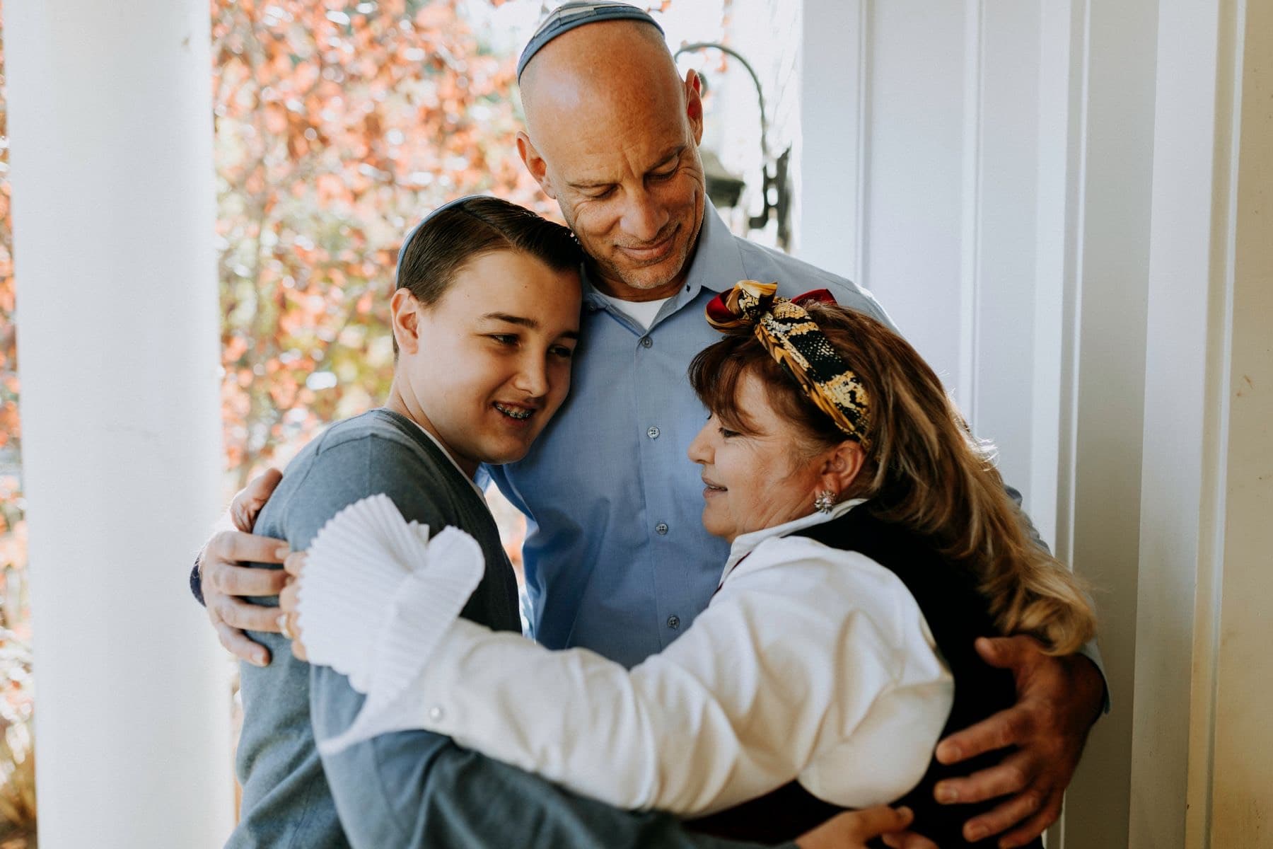 סבא עם כיפה מחבק את שני נכדיו